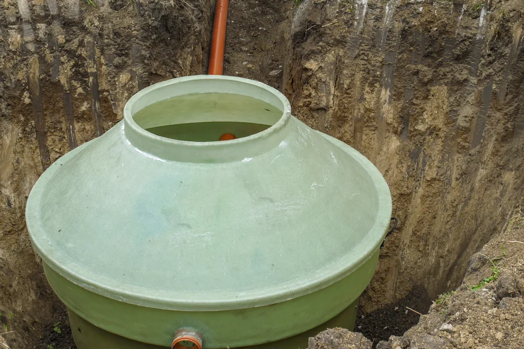 Green septic tank set in a freshly dug hole