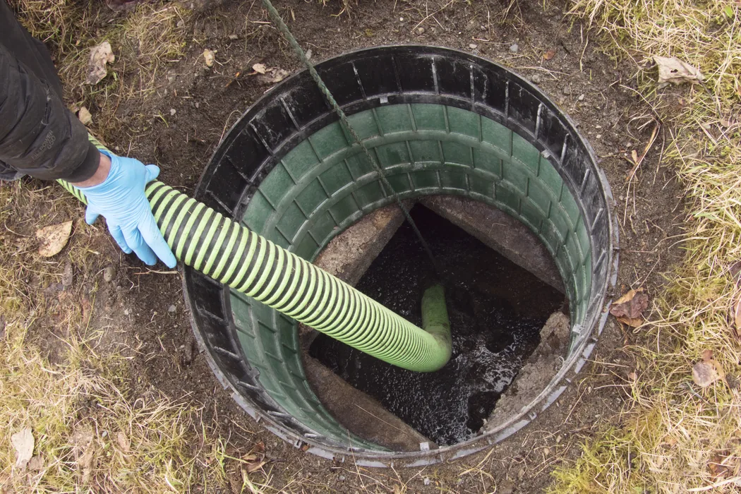 Pump hose running into a green septic riser